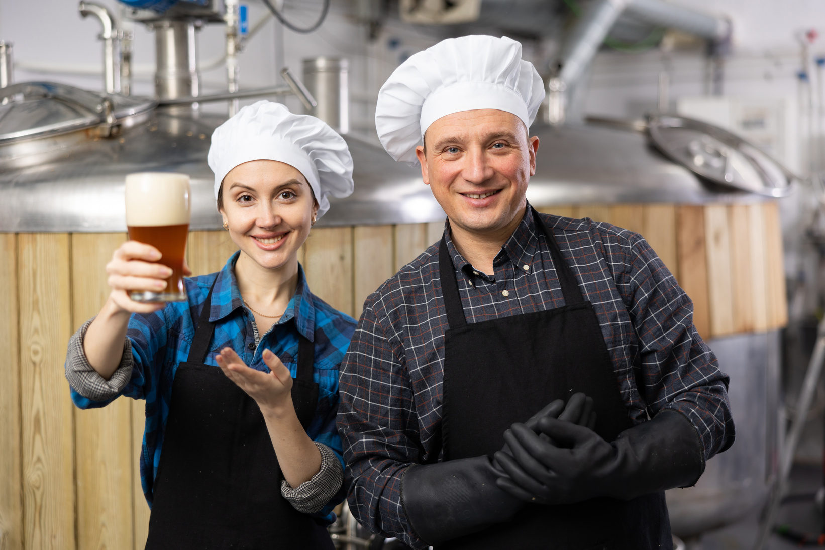 Smiling man and woman brewers presenting new beer in beer factory